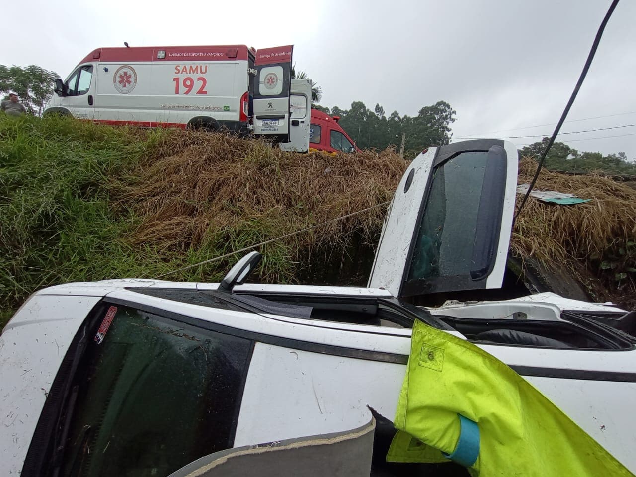Carro capota, cai em vala e um dos ocupantes fica preso às ferragens