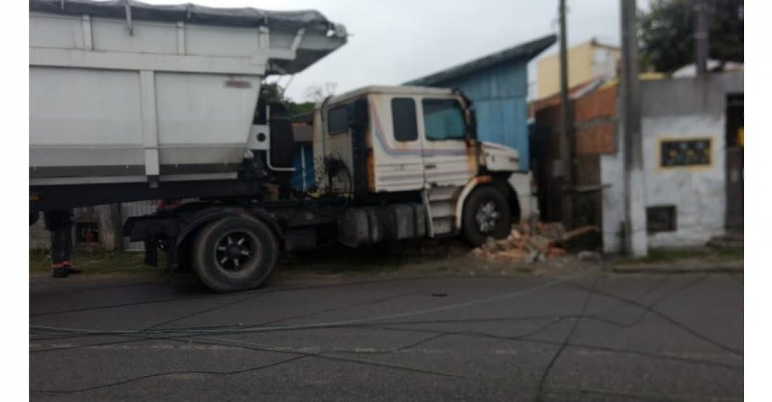 Caminhão desce avenida desgovernado, arranca poste e bate em muro